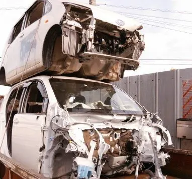 金属や部品を取り終えて積み重ねられた解体後の車体2台